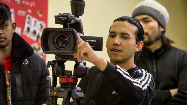 Foto von einem jungen erwachsenem, der hinter einer Kamera steht